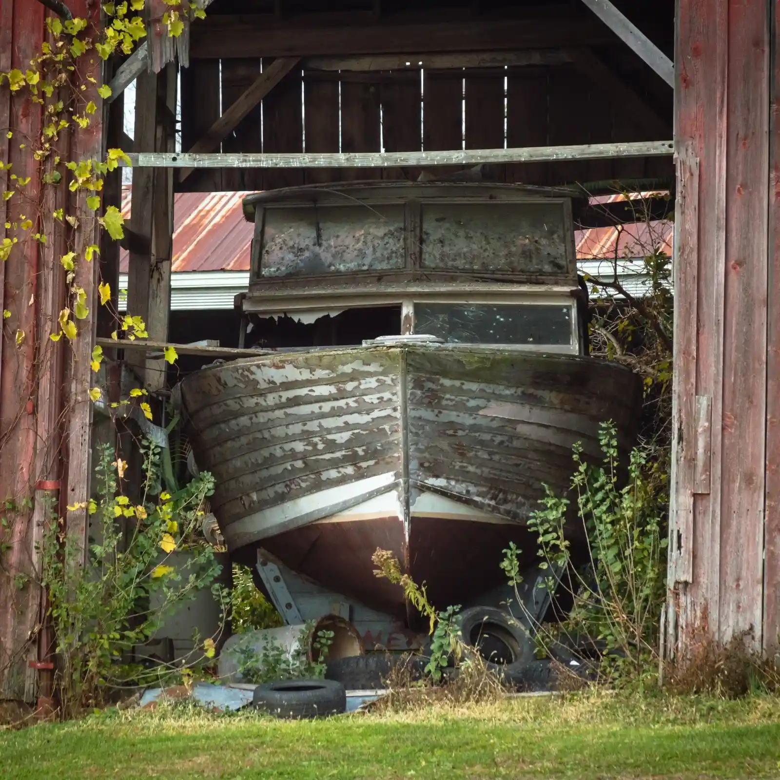 In an abandoned barn, an old wooden boat rests, long past its prime. Vines creep in from the edges, reclaiming the structure, as if the earth is trying to swallow it back into itself. The boat’s weathered hull is cracked and gray, telling stories of voyages never finished. Dust motes float in the filtered light, a quiet testament to forgotten dreams left to fade in dry dock silence.